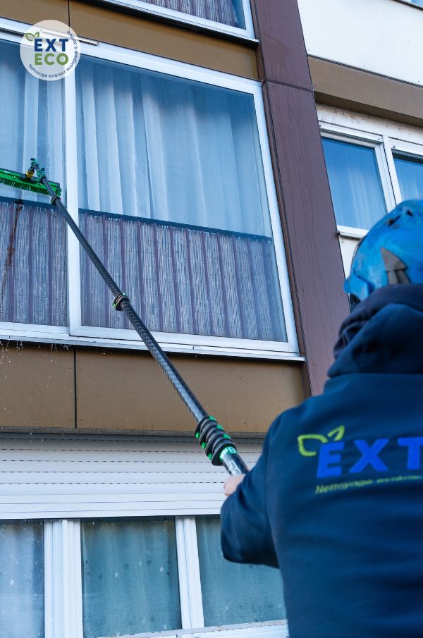 Le technicien procède au nettoyage des vitres à l'eau pure avec sa perche télescopique