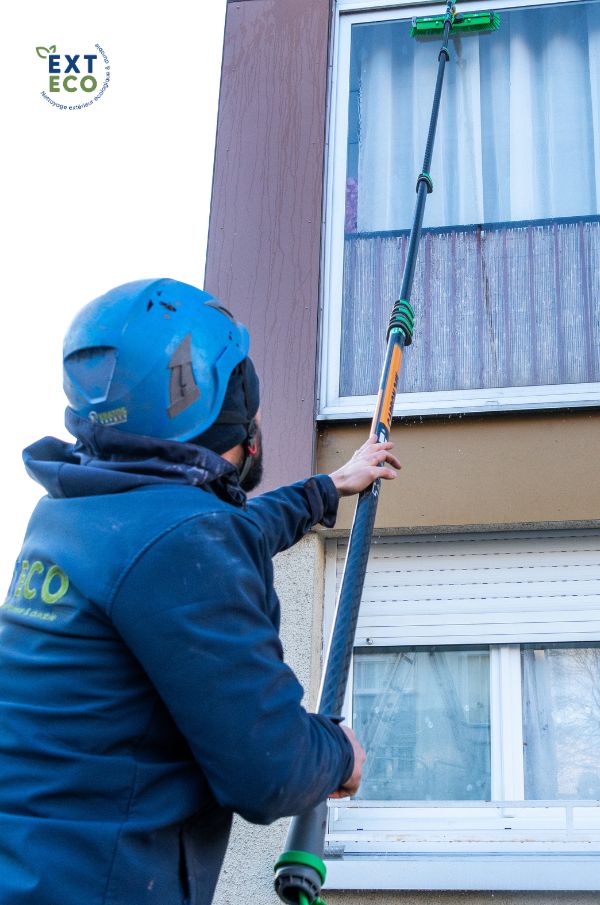 Le technicien nettoie les vitres à l'aide d'une perche télescopique à eau pure