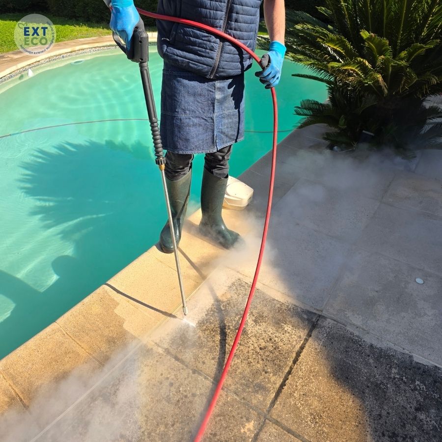 Technicien EXTECO qui nettoie à la vapeur basse pression les dalles autour d'une piscine