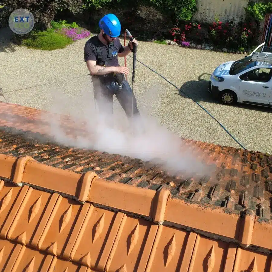 technicien qui réalise le nettoyage de toiture en Vendée sur tuiles en terre cuite